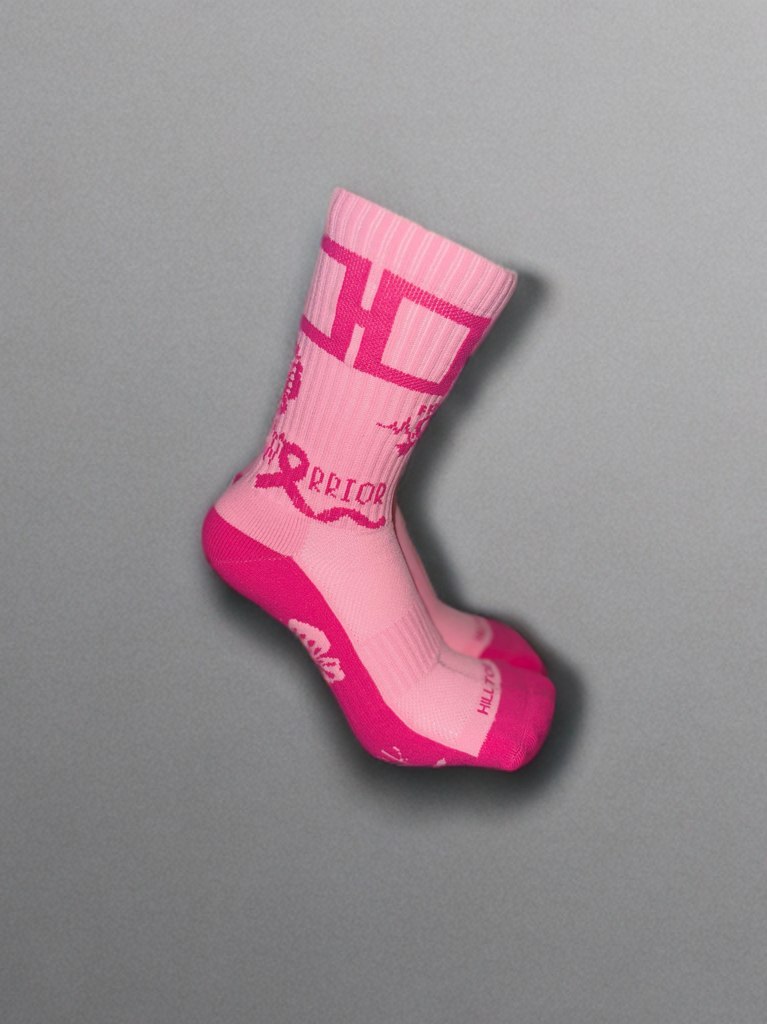 A pair of pink athletic socks with a bold 'WARRIOR' ribbon design and the Hill Toe brand logo on the ankle area.