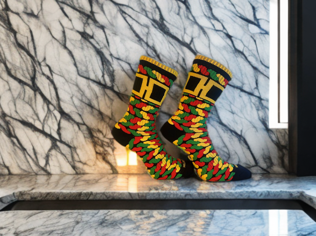 Juneteenth-inspired Hill Toe sock with red, green, gold, and black camo pattern, non-reflective H logo, and moisture-wicking performance knit.