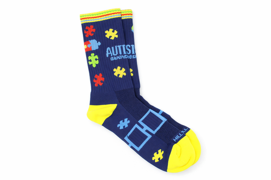 Navy blue sock with colorful puzzle piece design and 'Autism Awareness' text on a white background